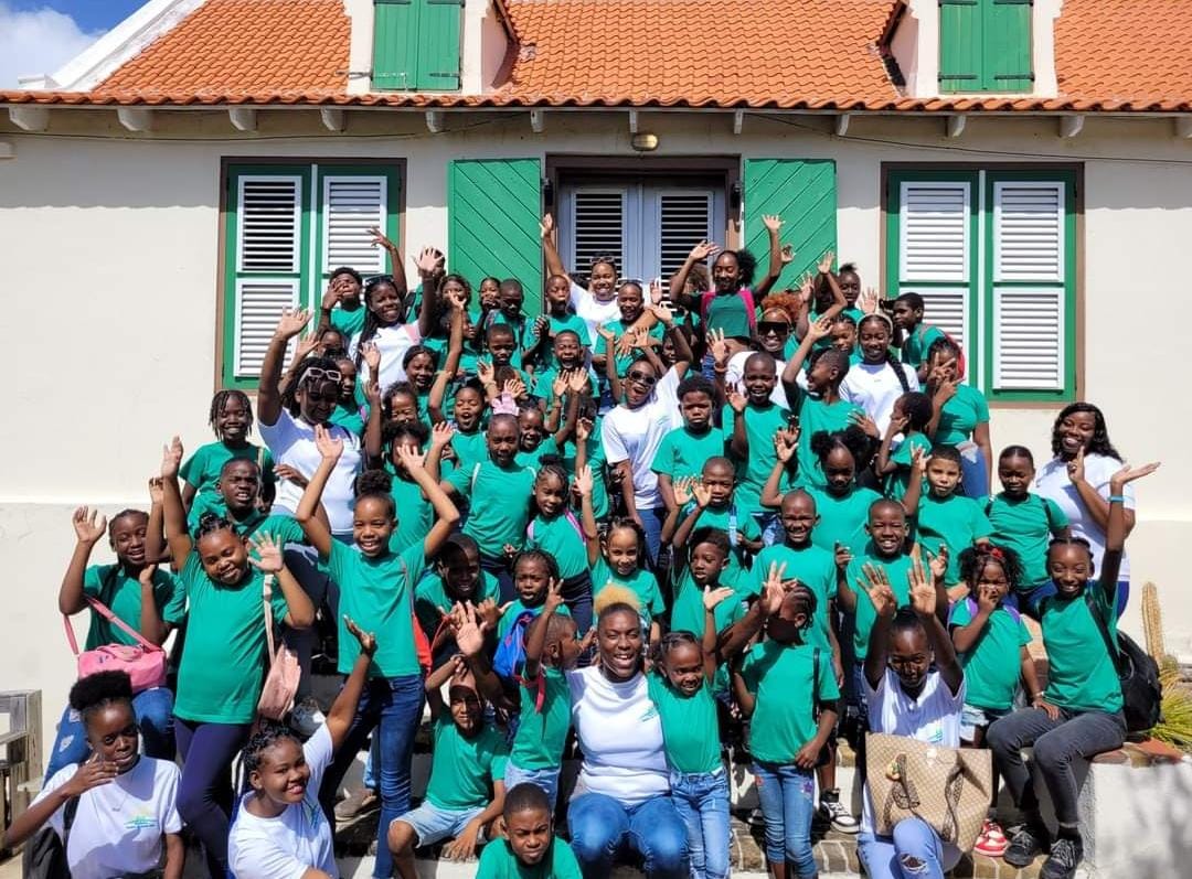 Groepsfoto van kinderen op Curacao gekleed in een groen schooluniform