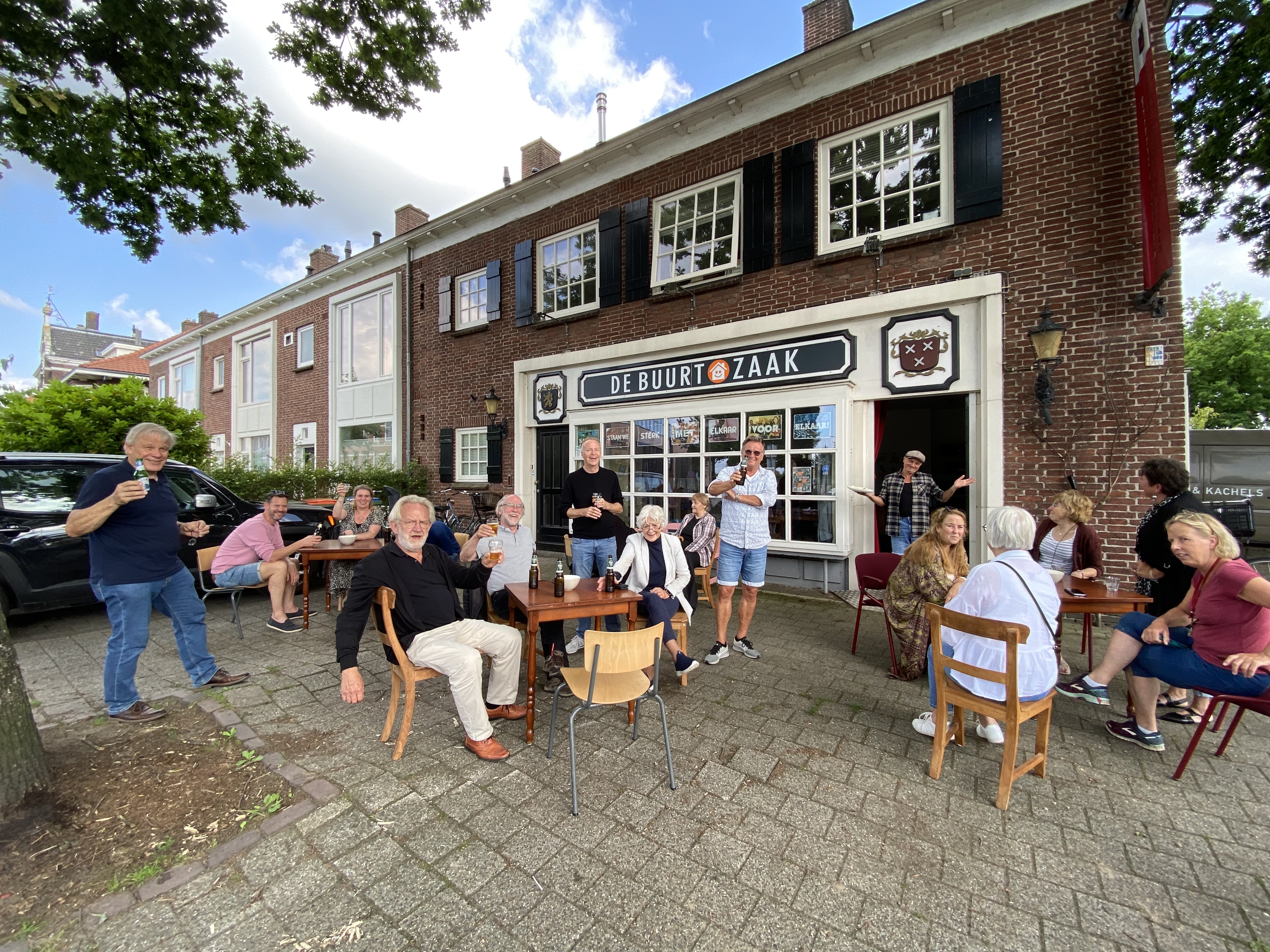 De Buurtzaak Mensen zitten in groepjes buiten